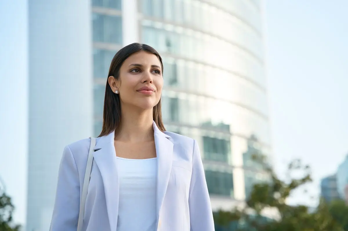 A composed professional woman standing outside an office building