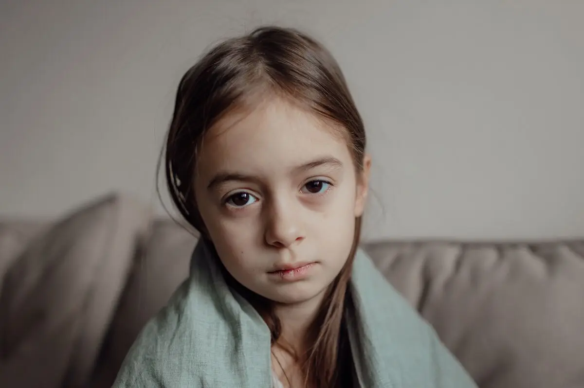A young girl wrapped in a blanket on a sofa