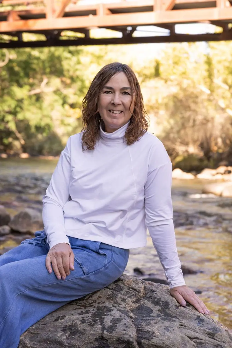 Melissa Hunt sitting on a rock beside a Colorado river
